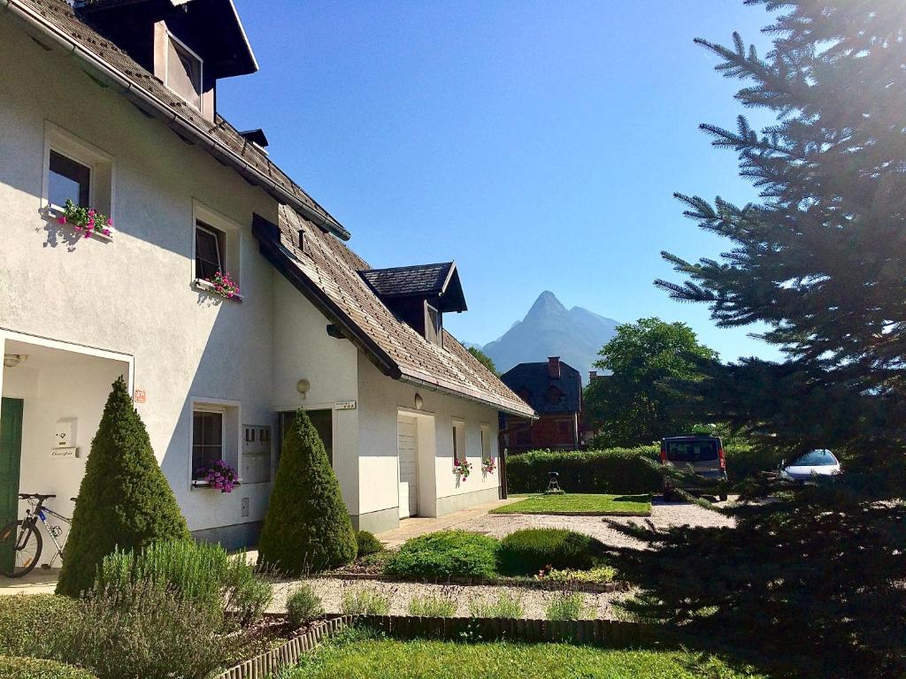 a white house with a mountain in the background at Apartments Alpha Center in Bovec
