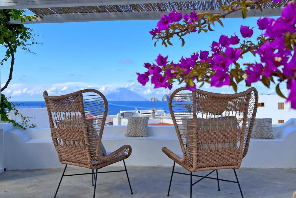 2 chaises assises sur une terrasse avec des fleurs violettes dans l'établissement Dependance La Caletta, à Panarea