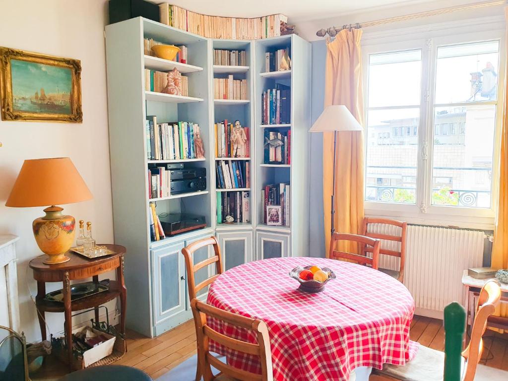 a dining room with a table and a book shelf at EXIGEHOME - Bel appartement en plein centre-ville in Boulogne-Billancourt
