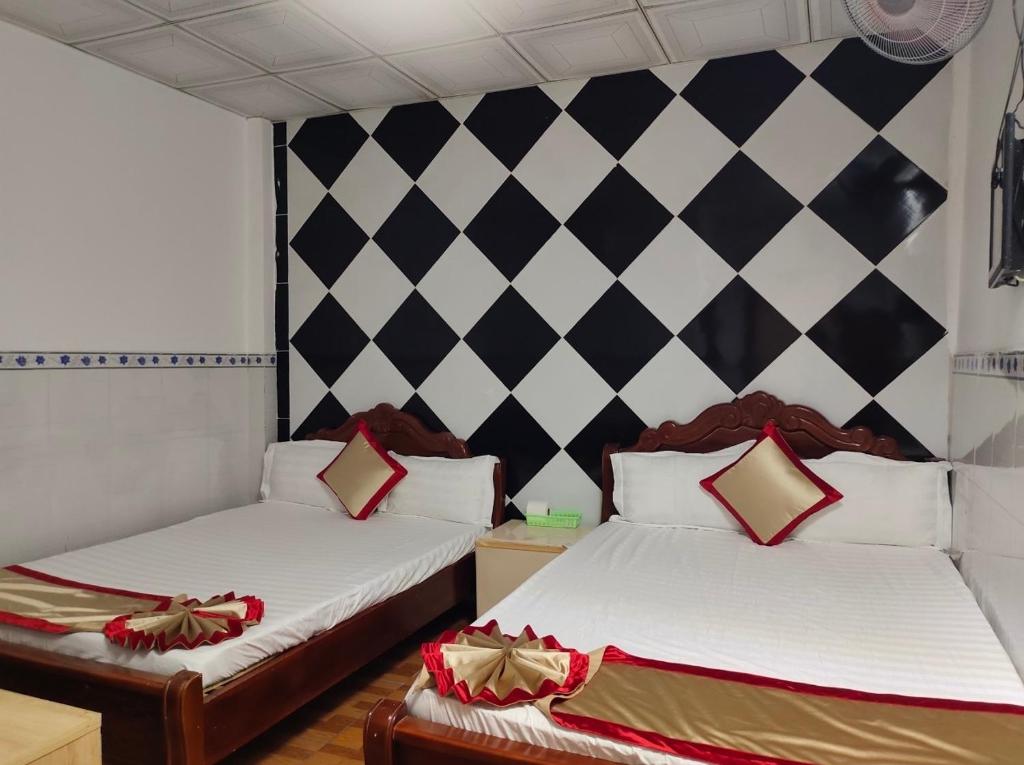 Hotel Thanh Vân في Thuan An: سريرين في غرفة ذات جدار أبيض وأسود