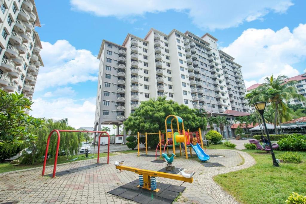 un parque infantil frente a un gran edificio de apartamentos en Glory Beach Resort 7+2 PAX Seaview Suite, en Port Dickson