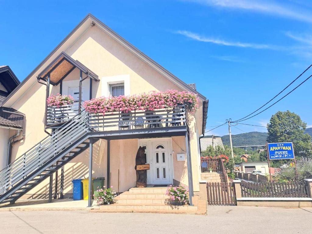 una pequeña casa con flores en los balcones y escaleras en Apartman Jezerane, en Jezerane