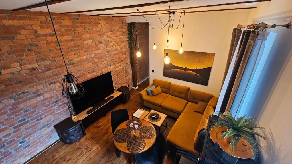 a living room with a couch and a brick wall at Dworcowa Centrum Apartament in Bydgoszcz