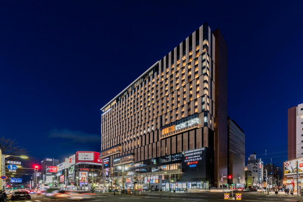 Un palazzo alto in una strada di città di notte di SAPPORO STREAM HOTEL a Sapporo