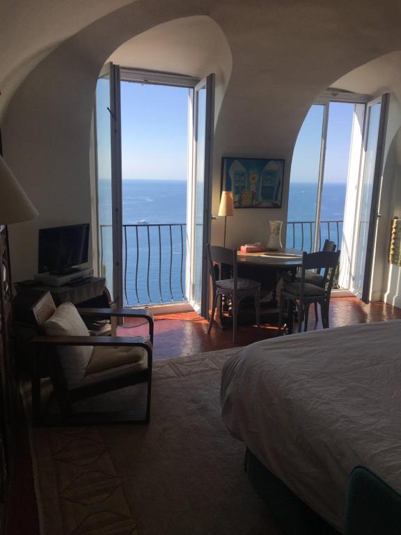 a bedroom with a bed and a table and a balcony at Dans village médiéval piétonnier, Suite exécutive vue mer exceptionnelle in Roquebrune-Cap-Martin