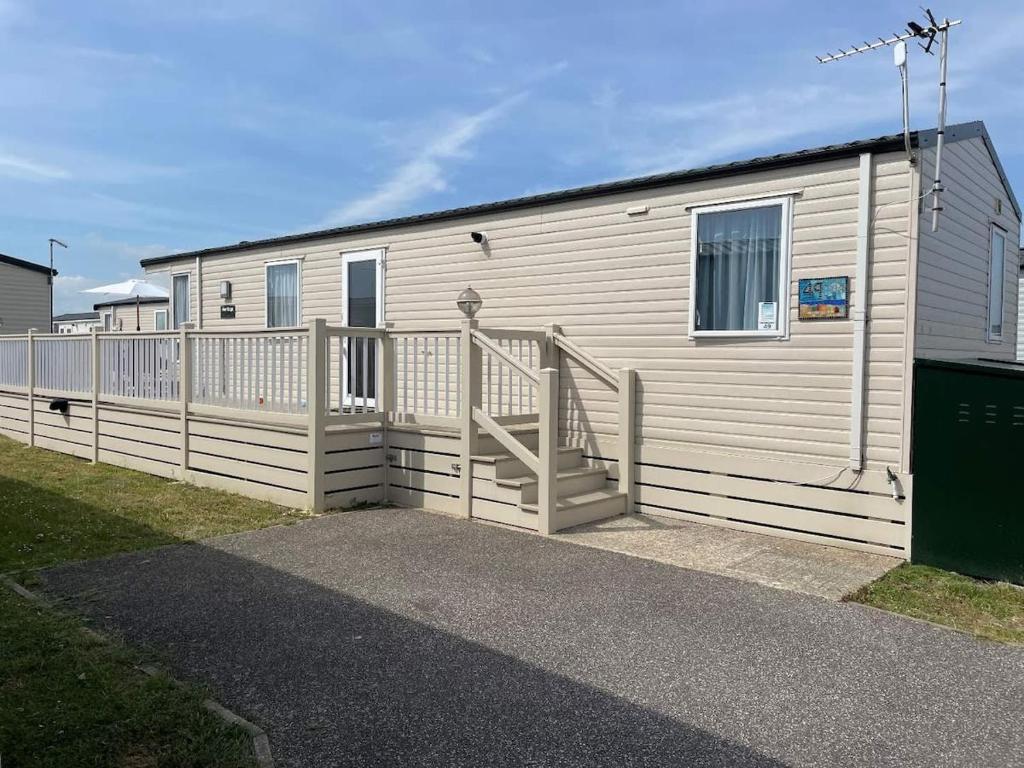 a building with a staircase next to a fence at 49 Bayside Cove Pevensey Bay Holiday Park in Pevensey