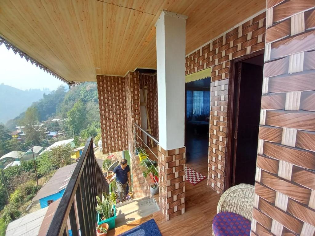uma casa numa colina com uma varanda em Pradhan's Homestay em Takdāh