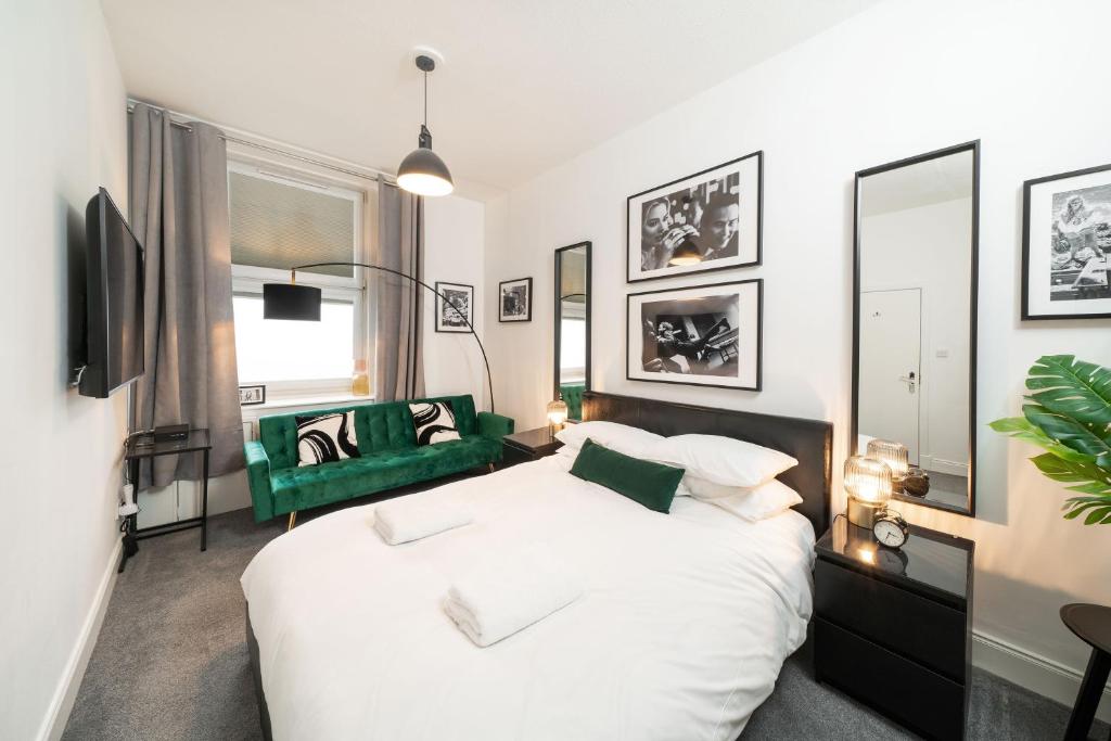 a bedroom with a white bed and a green chair at Princess Street Studios in Dundee