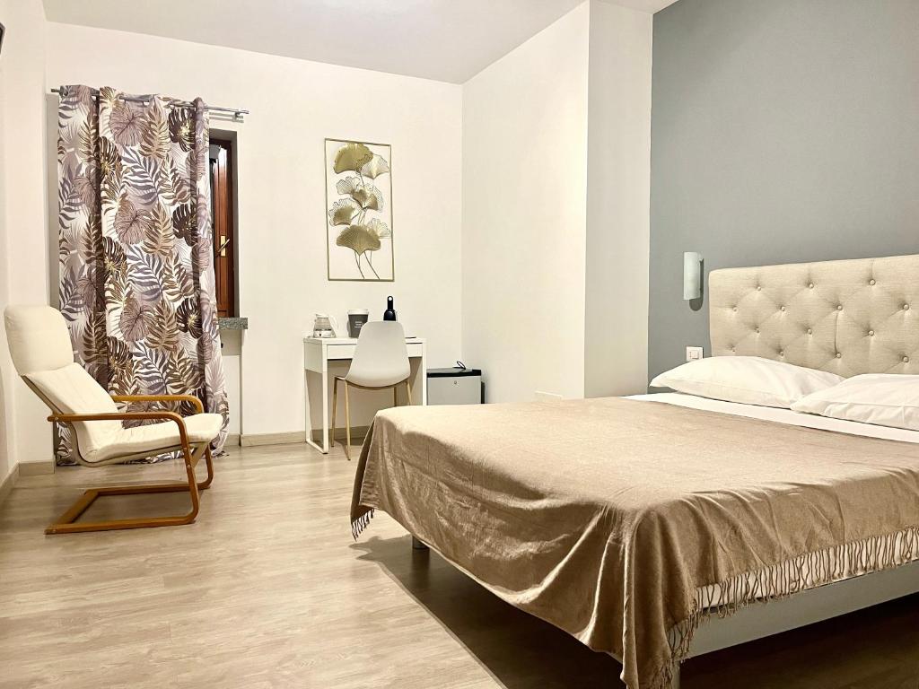 a bedroom with a bed and a chair and a table at Bella Vita Guesthouse -parcheggio privato interno in Arona
