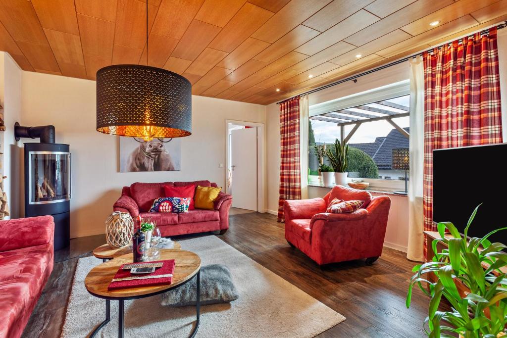 una sala de estar con 2 sofás rojos y una mesa. en Haus Frigger, en Olsberg