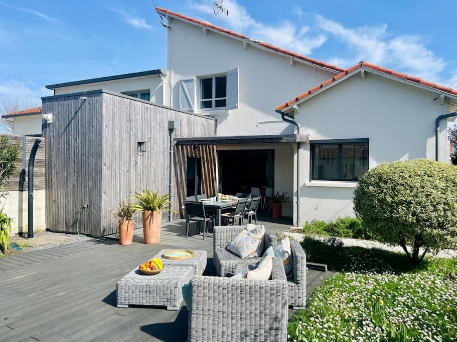 une terrasse avec des chaises en osier et une table en face d'une maison dans l'établissement Villa Les coquelicots La Baule, à La Baule
