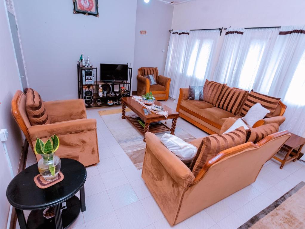 a living room with couches and chairs and a table at FARAJA HOMESTAY- Seamless Comfort in the Heart of the City - Free WiFi, Warm Hospitality, and Local Delights Await in Moshi