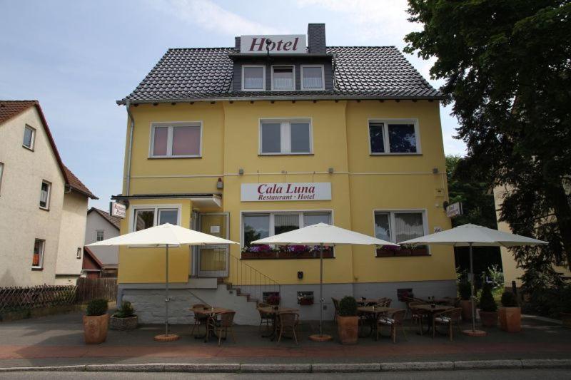 ein gelbes Gebäude mit Tischen und Sonnenschirmen davor in der Unterkunft Hotel Apartments Restaurant CALA LUNA in Marburg an der Lahn