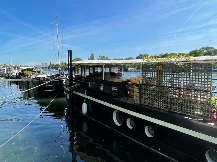 un bateau amarré à un quai dans l'eau dans l'établissement Dépaysement Art déco sur Seine à 2 pas de Paris, à Saint-Cloud