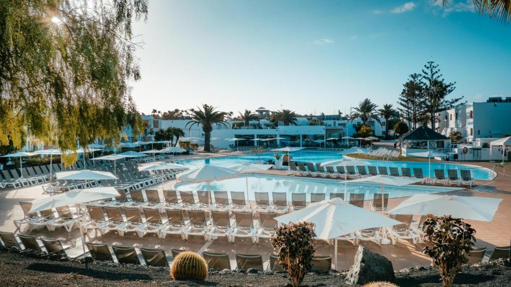 a resort with a pool and chairs and umbrellas at Labranda Bahía de Lobos in Corralejo