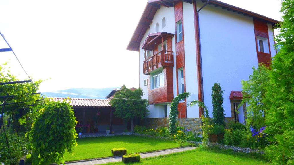 una casa con un patio verde delante de ella en Guest House Simona en Sapareva Banya