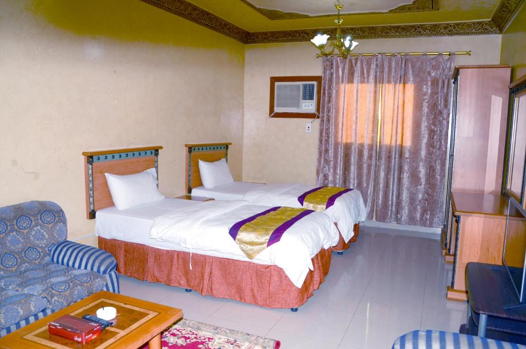 una habitación de hotel con 2 camas y una silla en درة 1 en Al Jubail