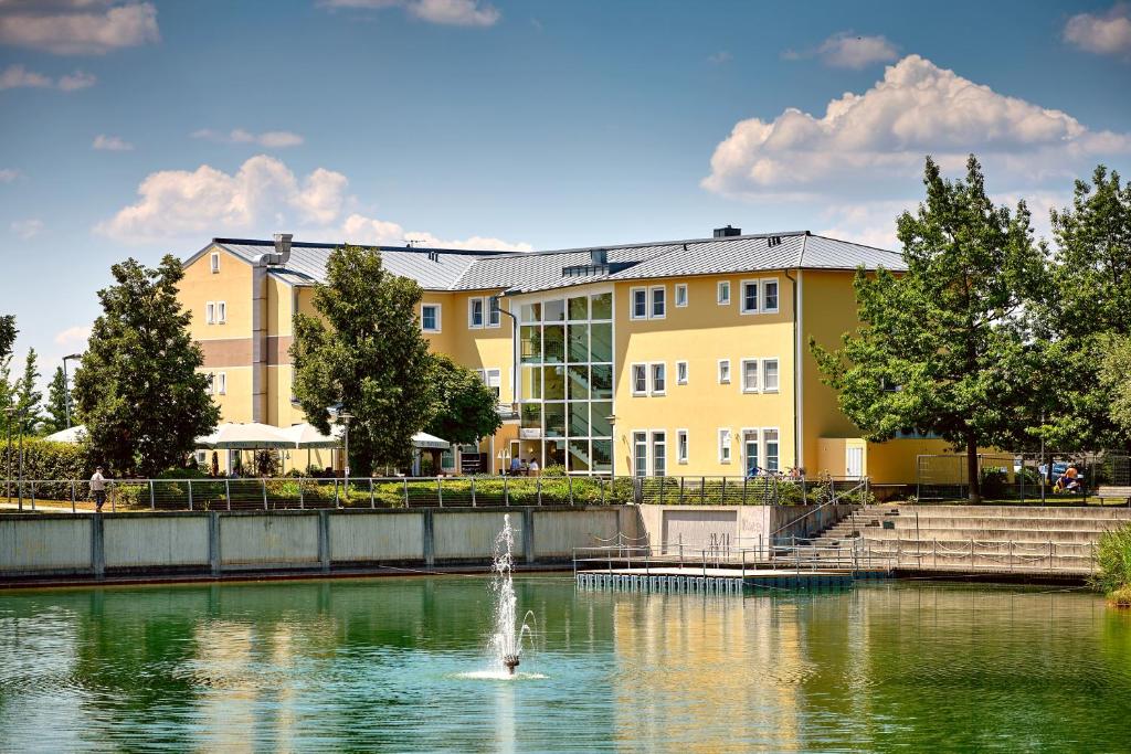 a building with a fountain in the middle of a lake at Hotel am See in Regensburg