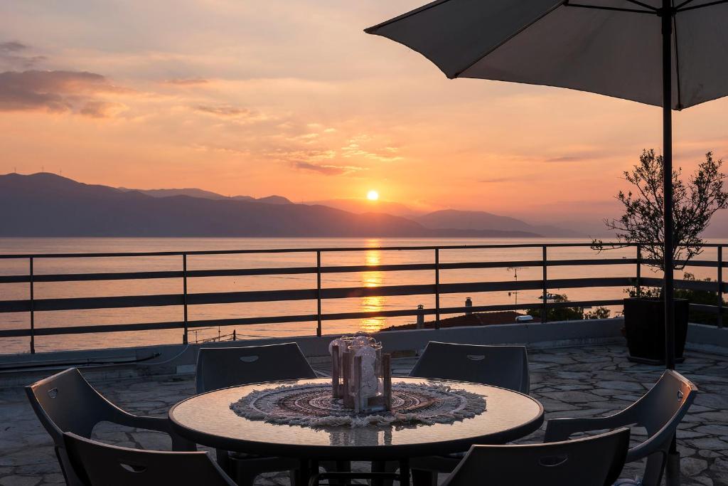 a table with chairs and an umbrella and the sunset at Selianitika Bay Γ2 Loft in Selianitika