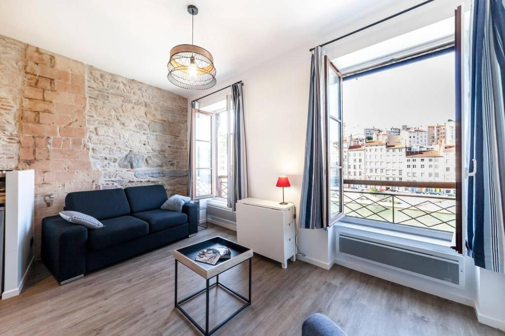 un salon avec un canapé et une grande fenêtre dans l'établissement Vieux Lyon avec vue sur la Saône AIL, à Lyon
