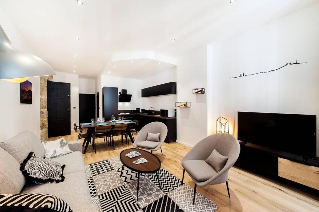 a living room with a couch and chairs and a television at Pure happiness -AC and balneotherapy AIL in Lyon