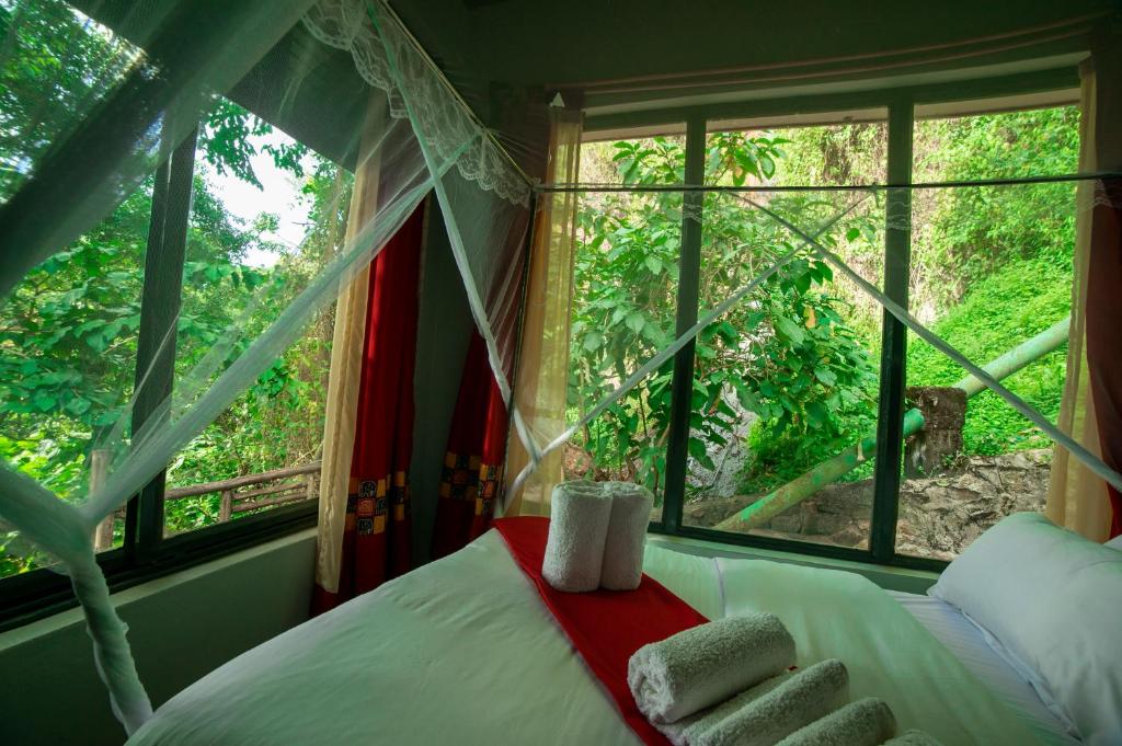 a bedroom with a bed with towels and a window at MISE CAVE LODGE in Kapchorwa