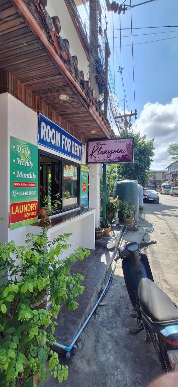 een motorfiets geparkeerd buiten een kamer te huur gebouw bij Kluay Mai Guest House in Chaweng Beach