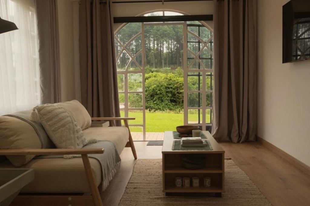 a living room with a couch and a large window at Fiddler's Green in Magoebaskloof
