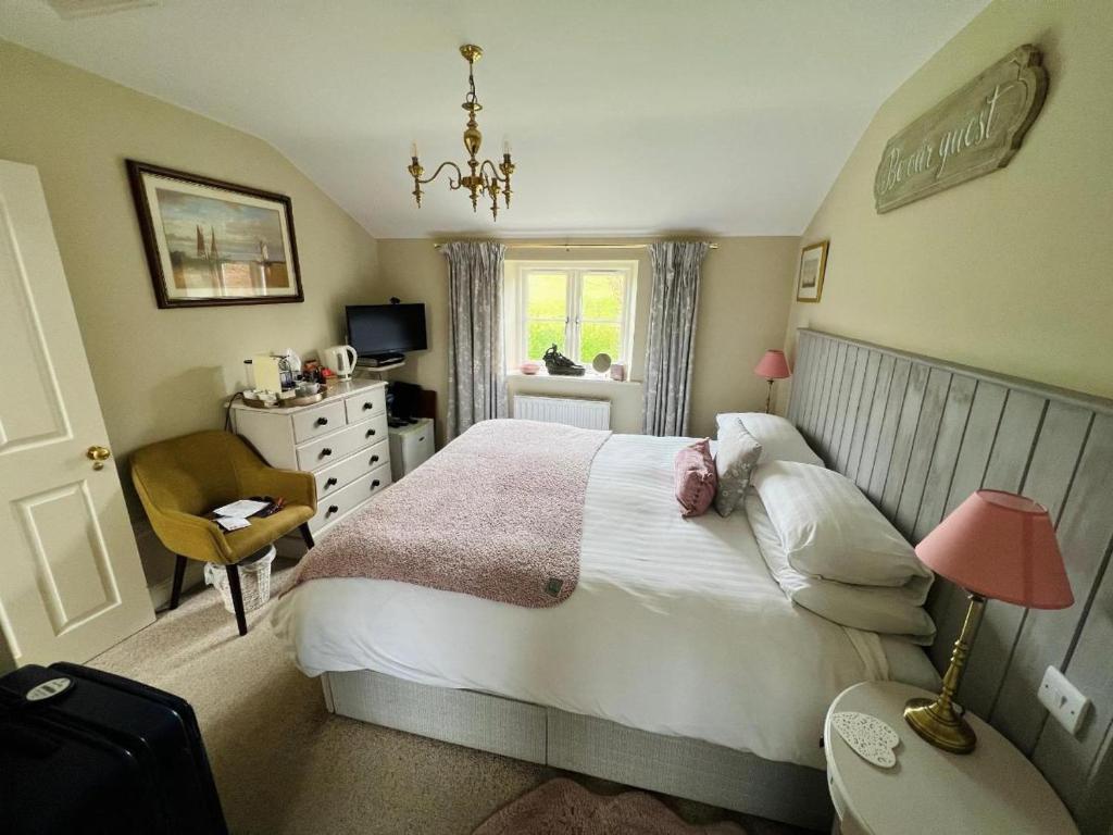 a bedroom with a bed and a chair and a window at Bridge House B & B Grassington in Grassington