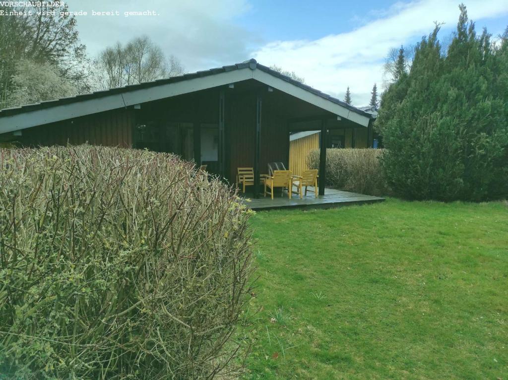 a black building with chairs and tables in a yard at Wald Chalet Nr 2 in Kellenhusen