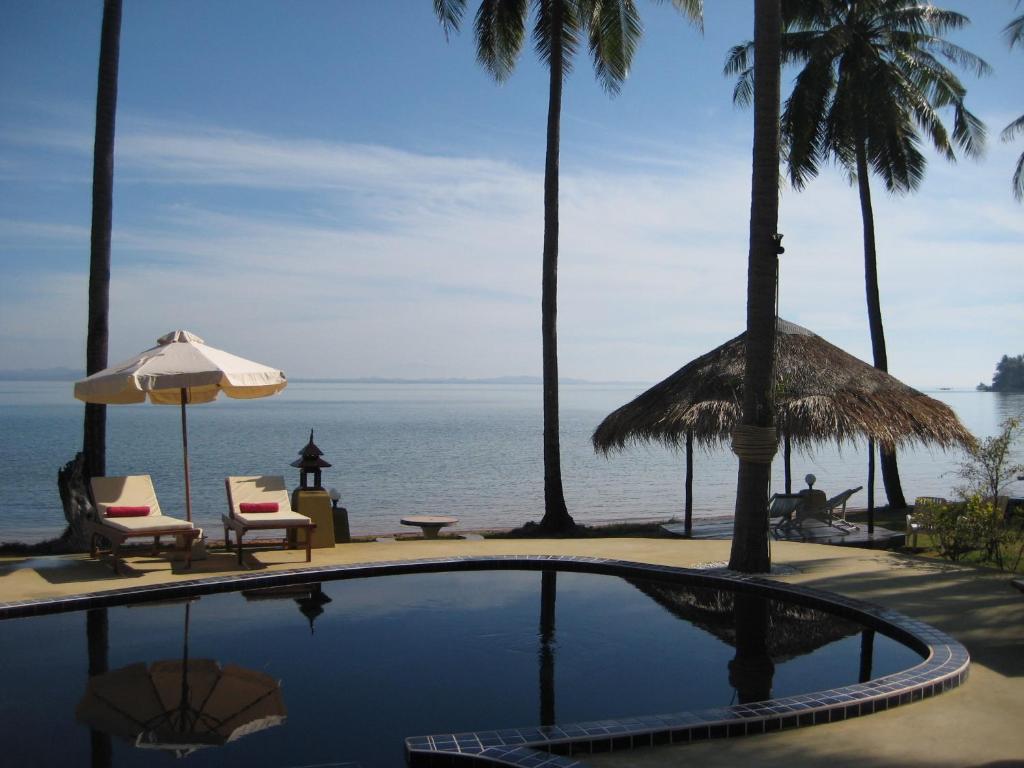 a swimming pool with chairs and a view of the ocean at Amber Sands Beach Resort in Ko Chang