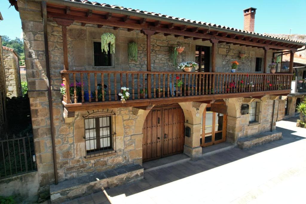 a stone house with a wooden gate and a balcony at La Calleja Real in Liérganes