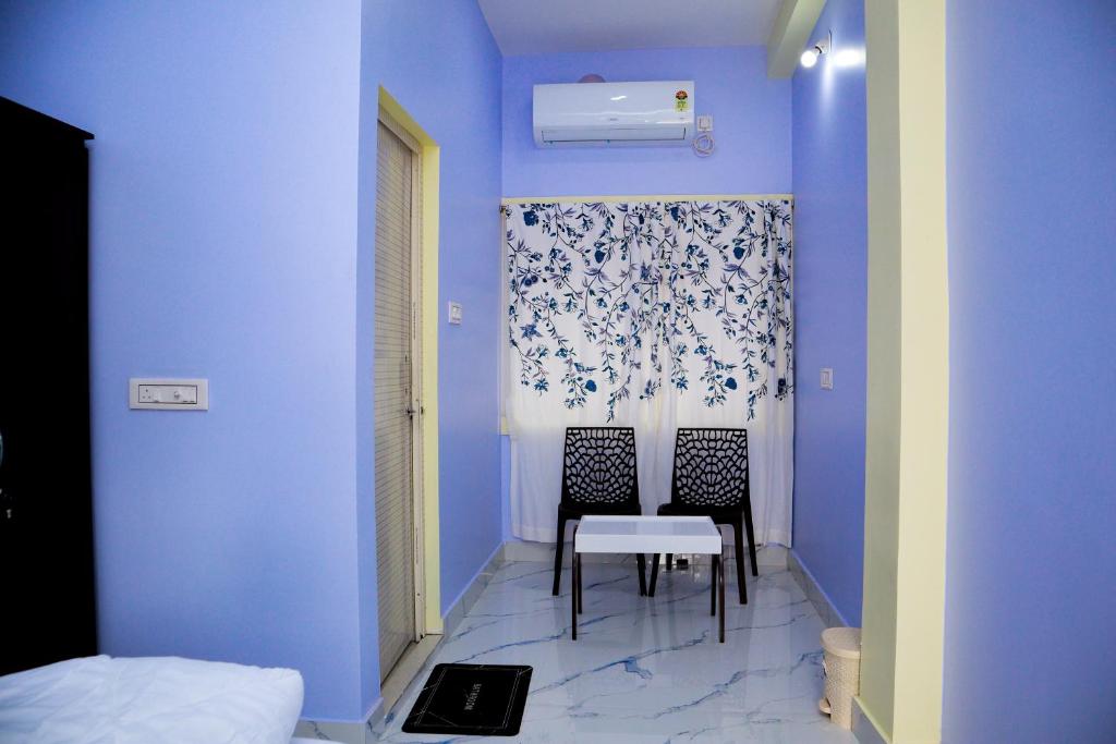 ein blaues Zimmer mit einem Tisch und zwei Stühlen in der Unterkunft Ichhepuron in Shānti Niketan