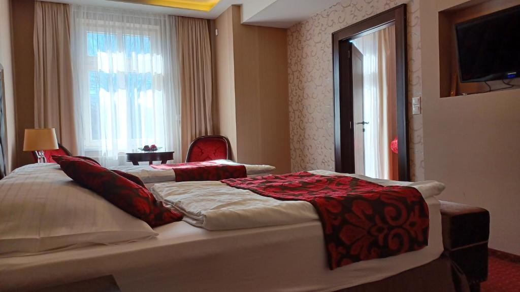 a hotel room with two beds and a window at Hotel Dvorana in Karlovy Vary