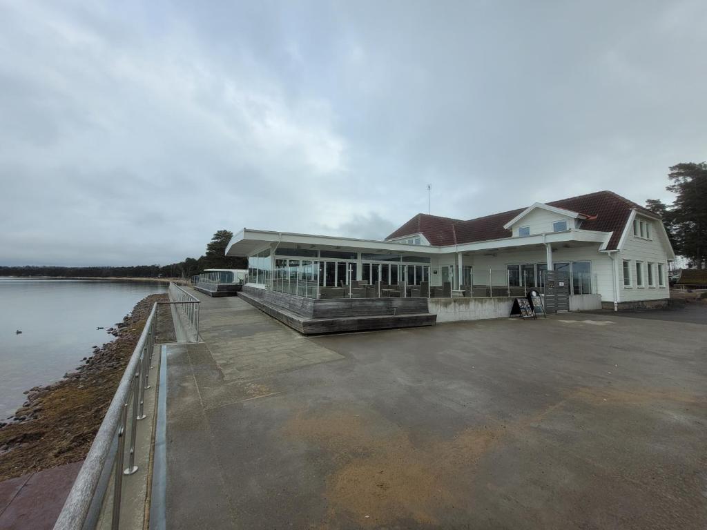 un grand bâtiment blanc à côté d'une étendue d'eau dans l'établissement Restaurang Sjövik, à Motala