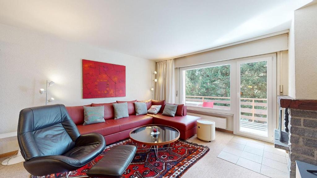 uma sala de estar com um sofá vermelho e uma cadeira em Charming 2-Bedroom in the Heart of Crans-Montana em Crans-Montana