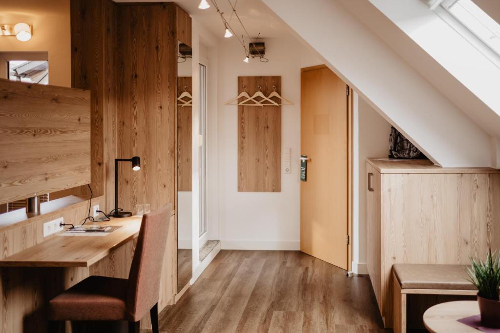 a room with a desk and a staircase with wooden walls at Hotel Garni Stube in Königschaffhausen