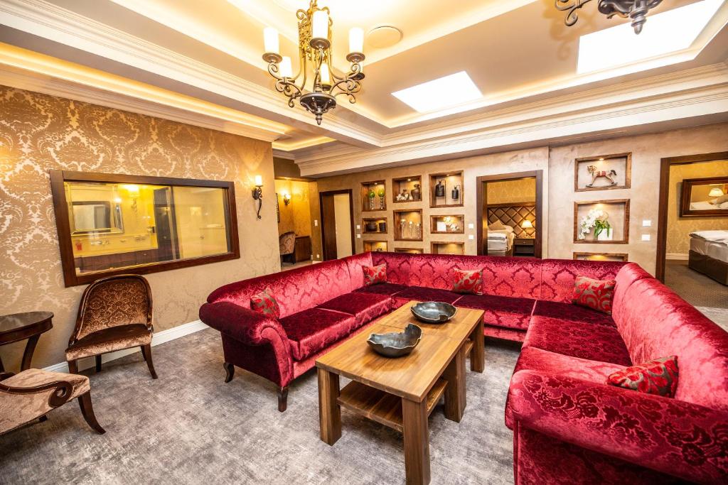 a living room with a red couch and a table at Hotel Dvorana in Karlovy Vary