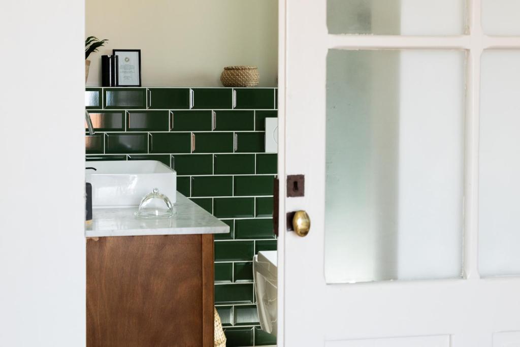 a bathroom with a sink and a green tiled wall at Casa Idalia Boutique Hotel in Comporta