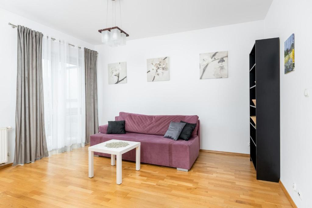sala de estar con sofá púrpura y mesa en Borkowska Comfort Apartment en Cracovia