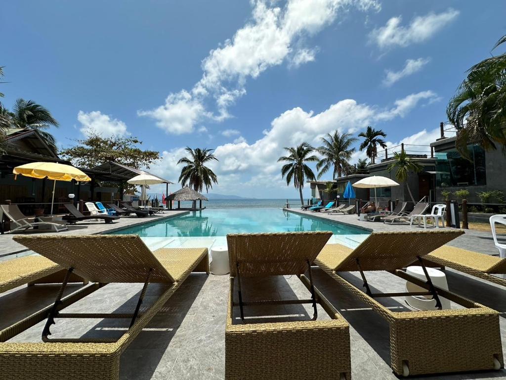 a pool with chairs and a view of the ocean at The Sea Resort Haad Rin in Haad Rin