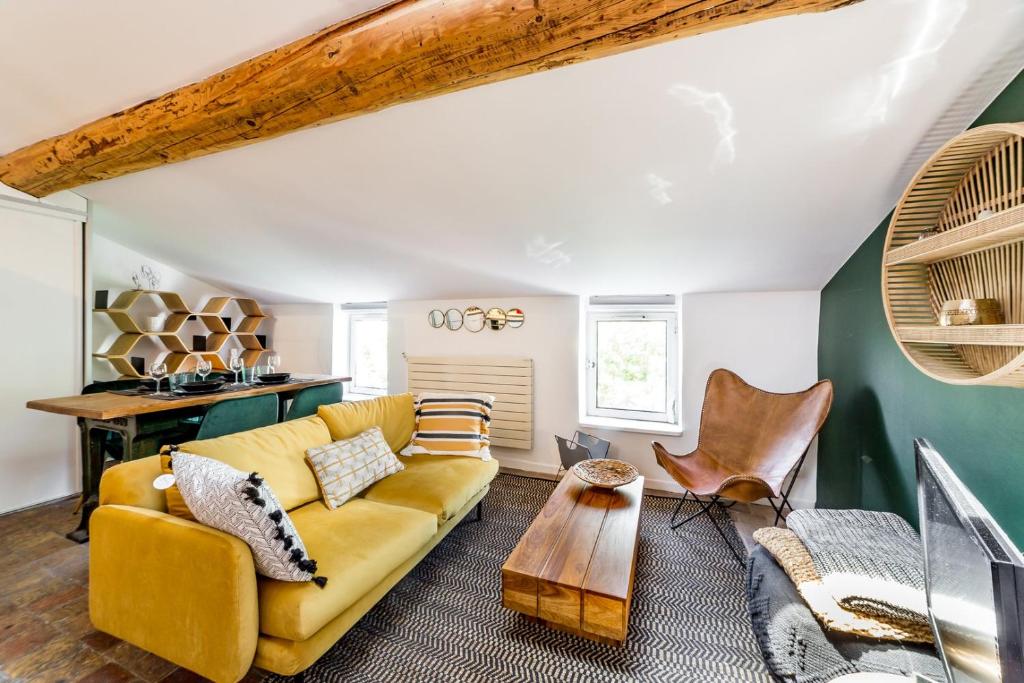 un salon avec un canapé jaune et une table dans l'établissement Le loft des artistes de la Croix-Rousse AIL, à Lyon