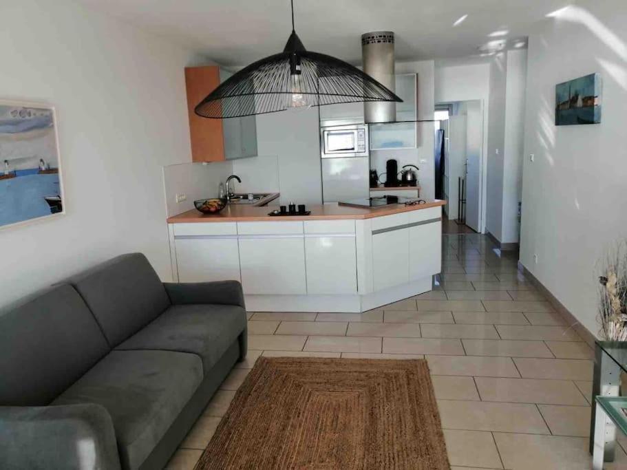 a living room with a couch and a kitchen at Superbe Appartement Vue Mer T3 70m2 in Mauguio