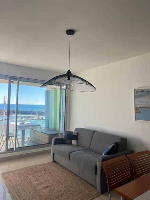 a living room with a couch and a large window at Superbe Appartement Vue Mer T3 70m2 in Mauguio