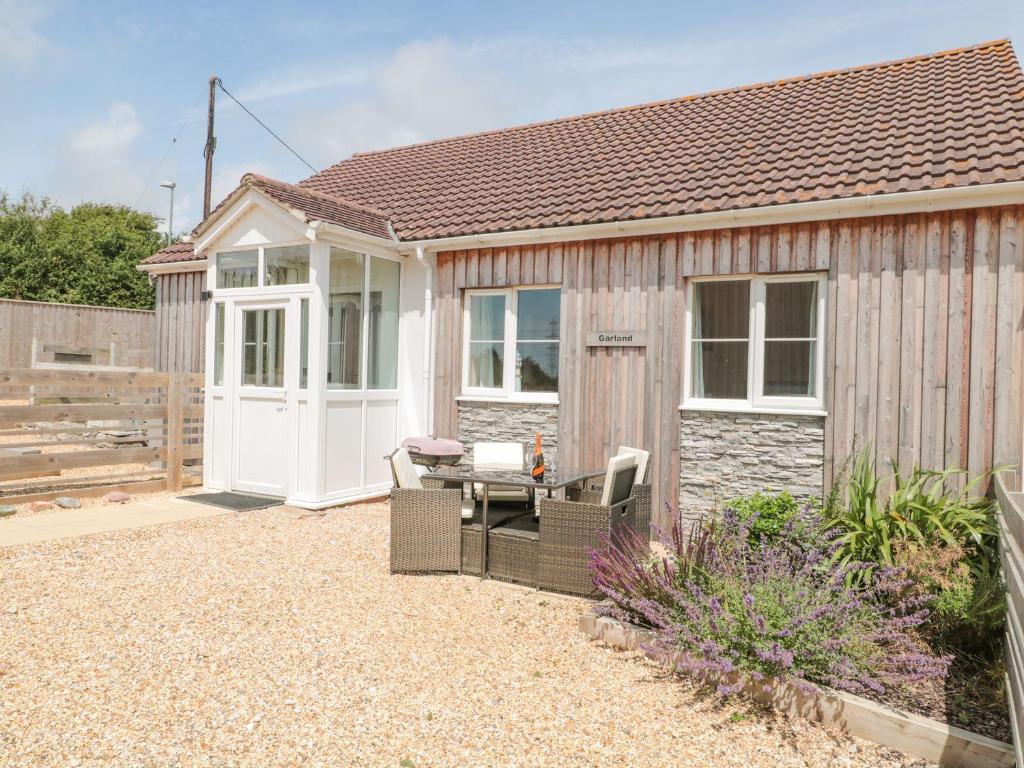 a small house with a white door and a patio at Garland in Weymouth