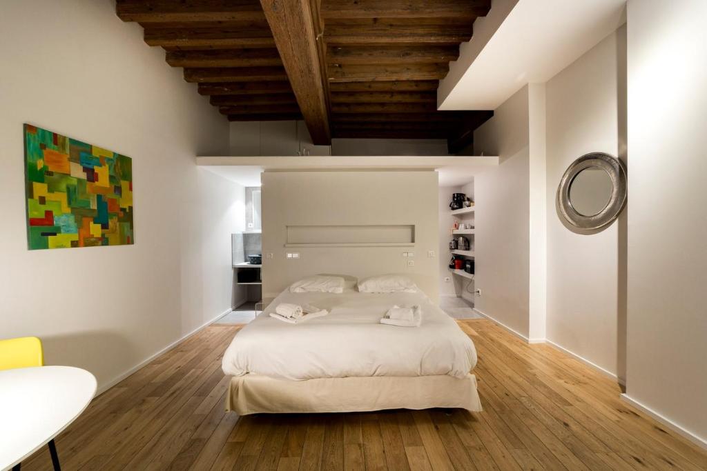 - une chambre avec un lit blanc et un plafond en bois dans l'établissement Le Petit Change - Studio tout équipé en Lyon AIL, à Lyon