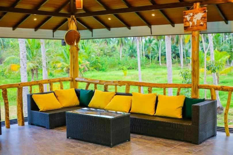 a screened in porch with yellow and green pillows at Liverpool Estate - Chilaw in Chilaw