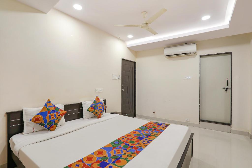 ein Schlafzimmer mit einem Bett mit bunten Kissen darauf in der Unterkunft FabExpress Girija Inn in Nagpur