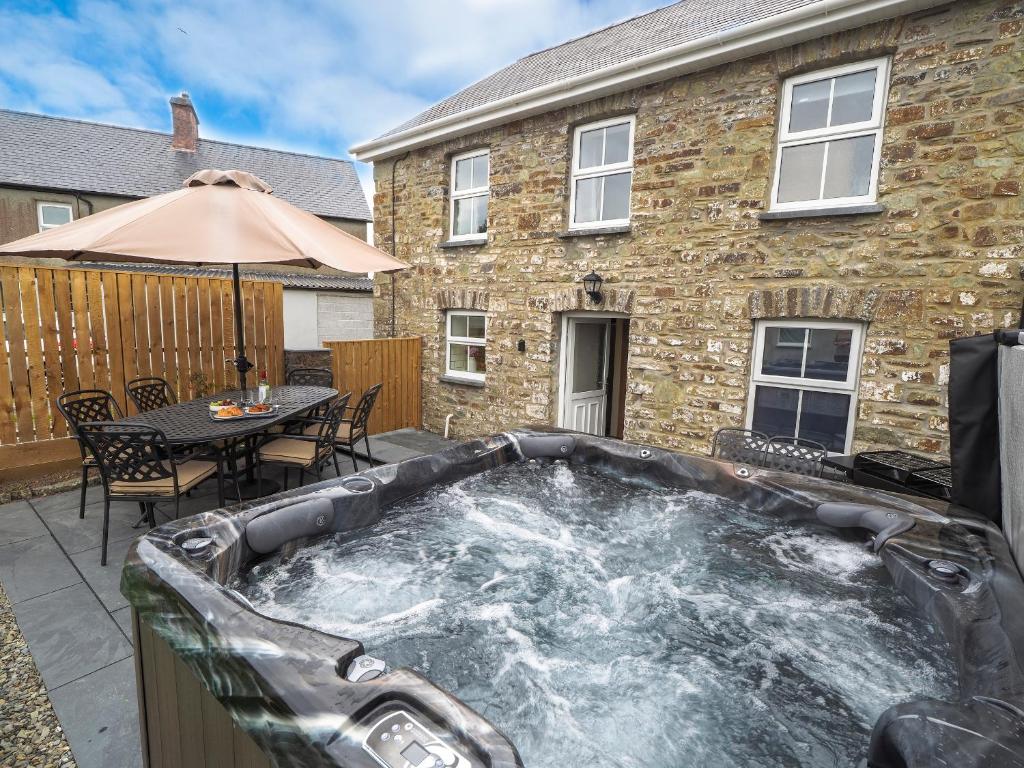 a hot tub on a patio in front of a house at Bryndalis Ciliau Aeron in Ciliau-Aeron