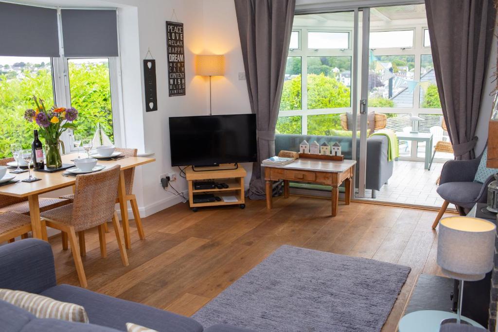 ein Wohnzimmer mit Fernseher und Tisch und Stühlen in der Unterkunft Tryweryn Cottage Saundersfoot in Saundersfoot